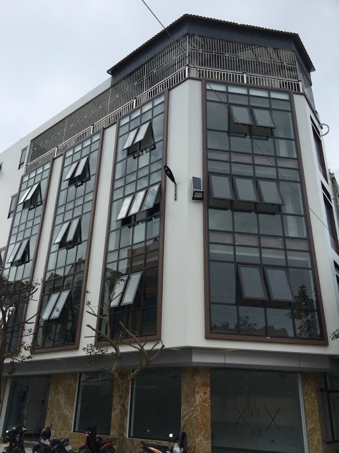 Mặt tiền tòa nhà văn phòng nhiều tầng với hệ cửa kính khung nhôm hiện đại và tầng trệt ốp đá