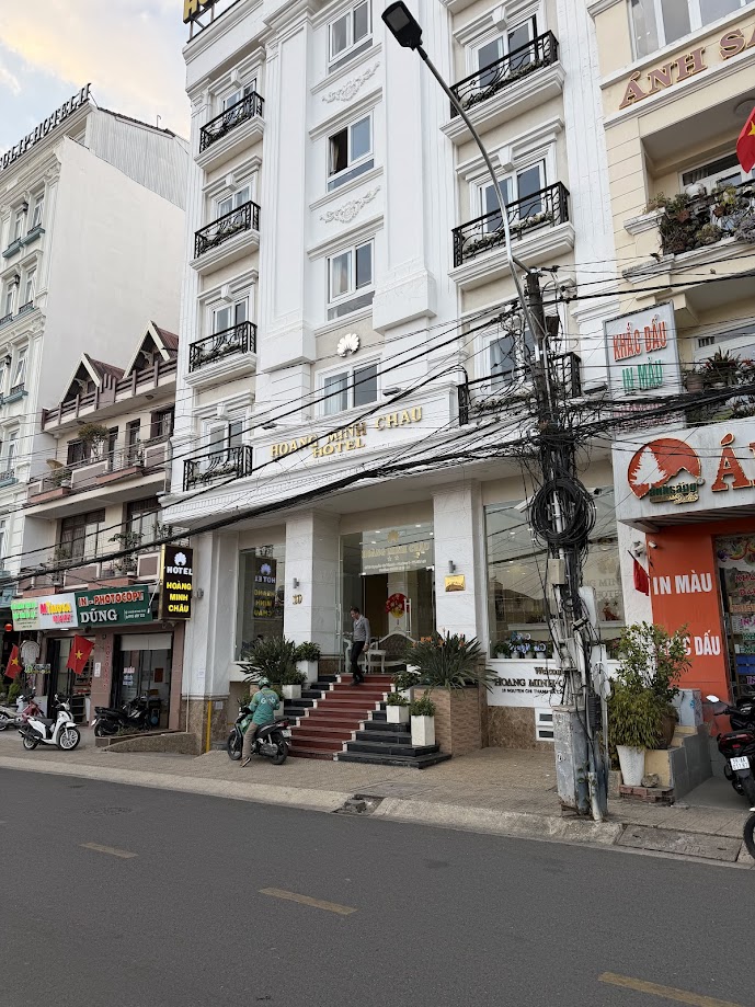 Mặt tiền khách sạn Hoàng Minh Châu với lối vào bậc thang đỏ và biển hiệu vàng trên phố Việt Nam