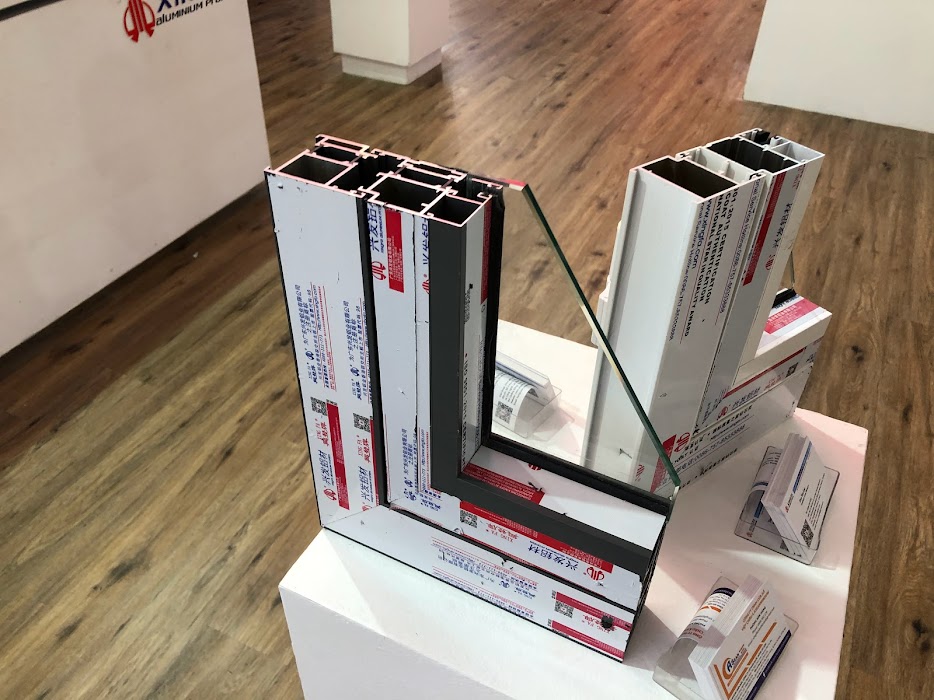 Mẫu khung cửa nhôm kính chữ L trưng bày trên bục trong showroom sàn gỗ
