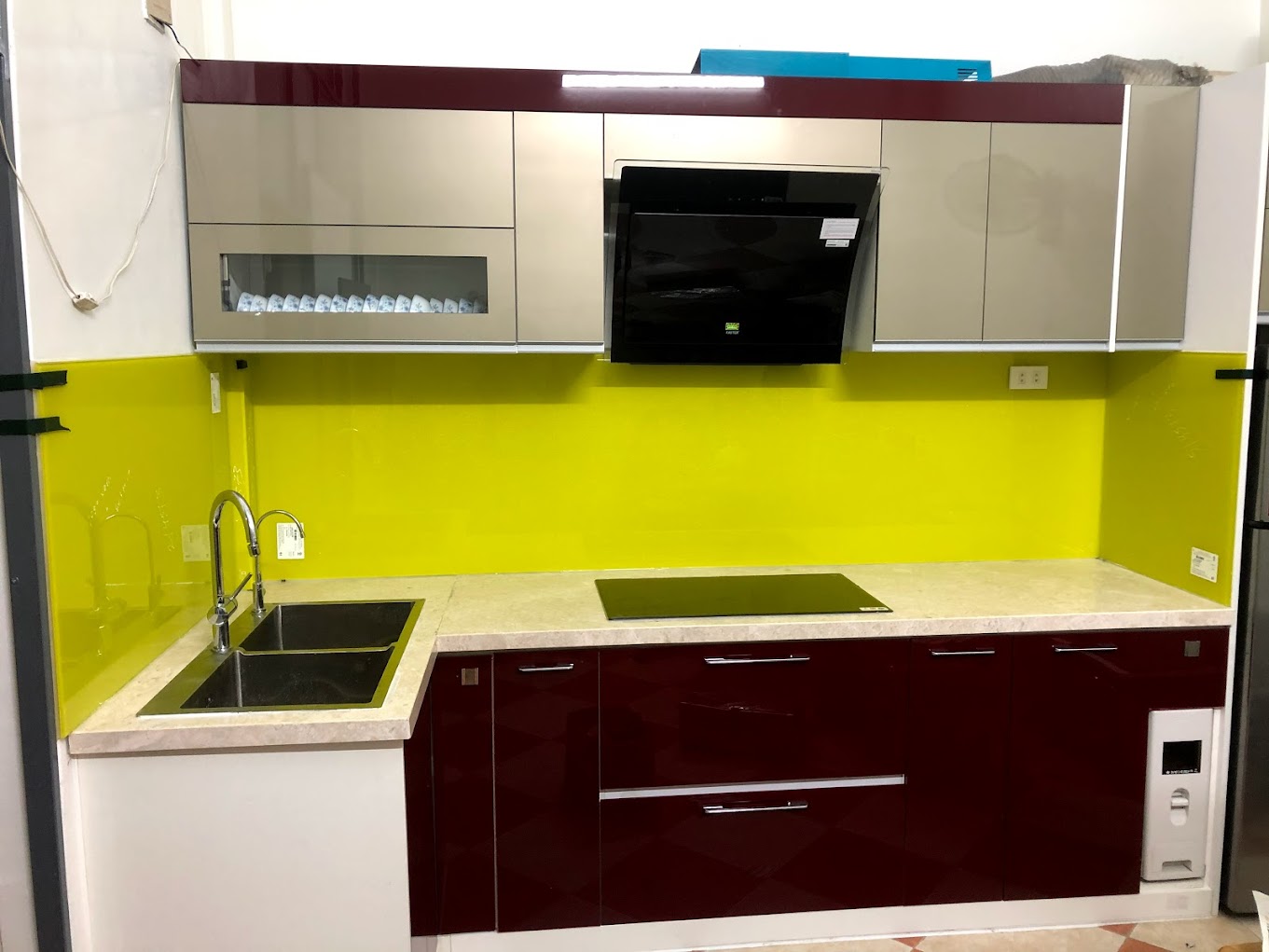 Tủ bếp hiện đại với mặt đá, bồn rửa đôi, bếp từ âm và kính ốp bếp màu vàng nổi bật