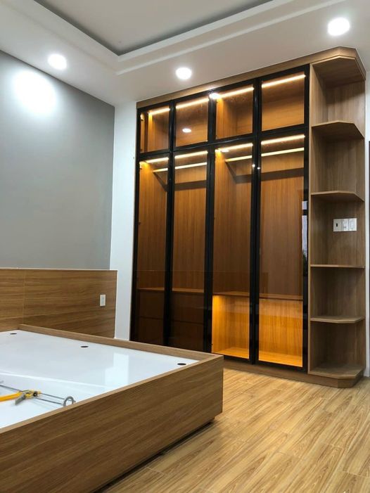 Tủ quần áo gỗ cánh kính trà đỏ có đèn LED và giường gỗ hiện đại trong phòng ngủ sáng