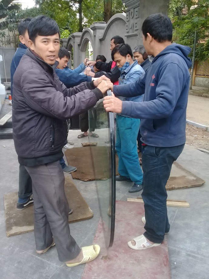 Nhóm thợ đang vận chuyển tấm kính lớn trong công trình ngoài trời