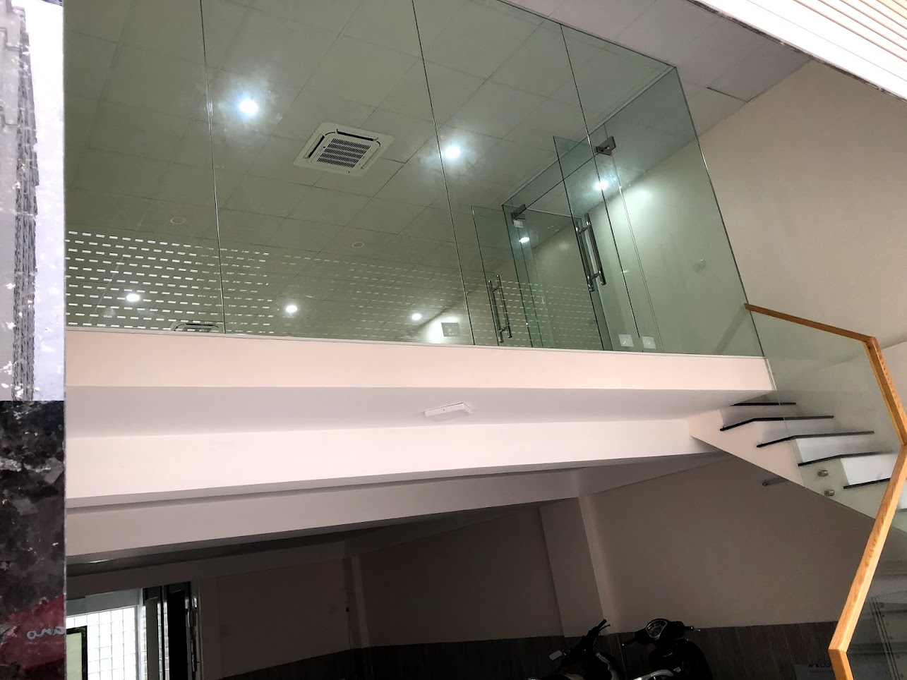 Gác lửng văn phòng kính cường lực với cầu thang tay vịn gỗ trong nhà phố hiện đại