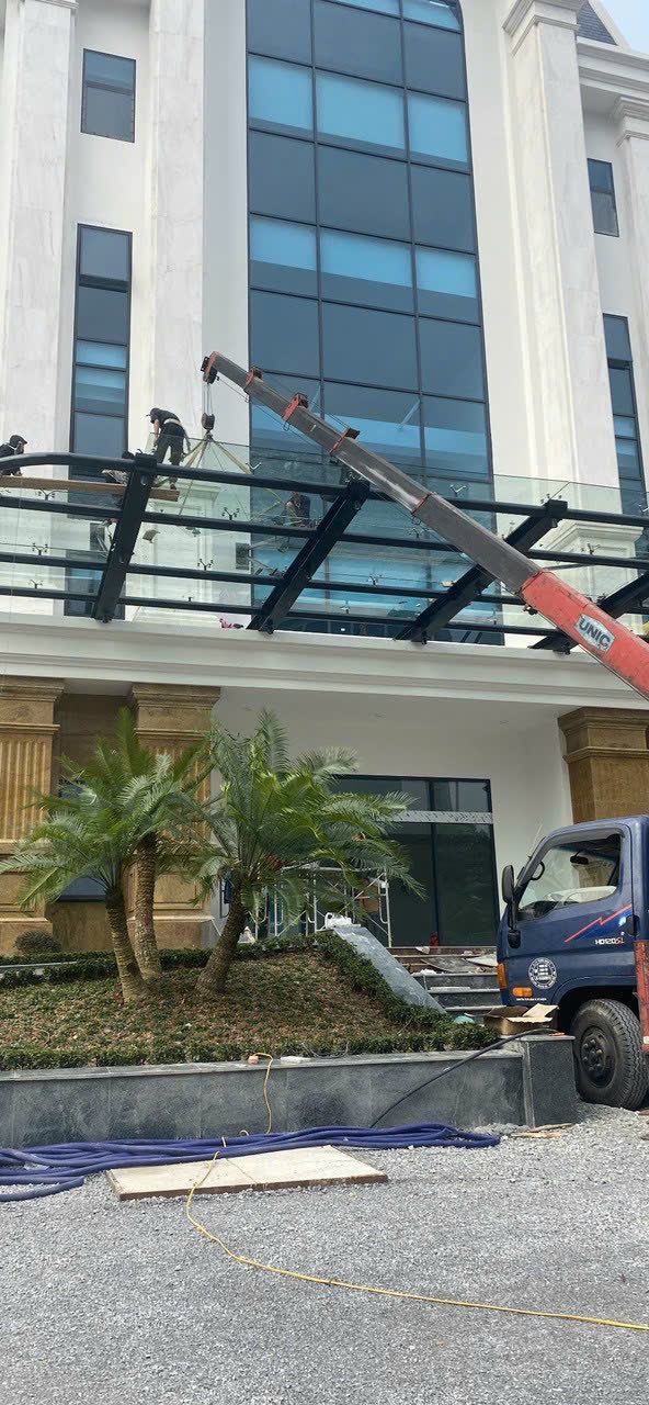 Thi công lắp đặt mái kính cường lực mặt tiền tòa nhà bằng xe cẩu và khung thép